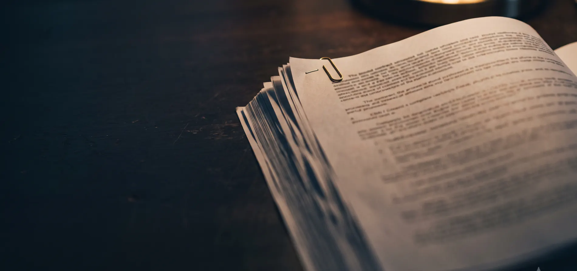 Contrato impreso abierto sobre un escritorio oscuro, con un clip de bronce
